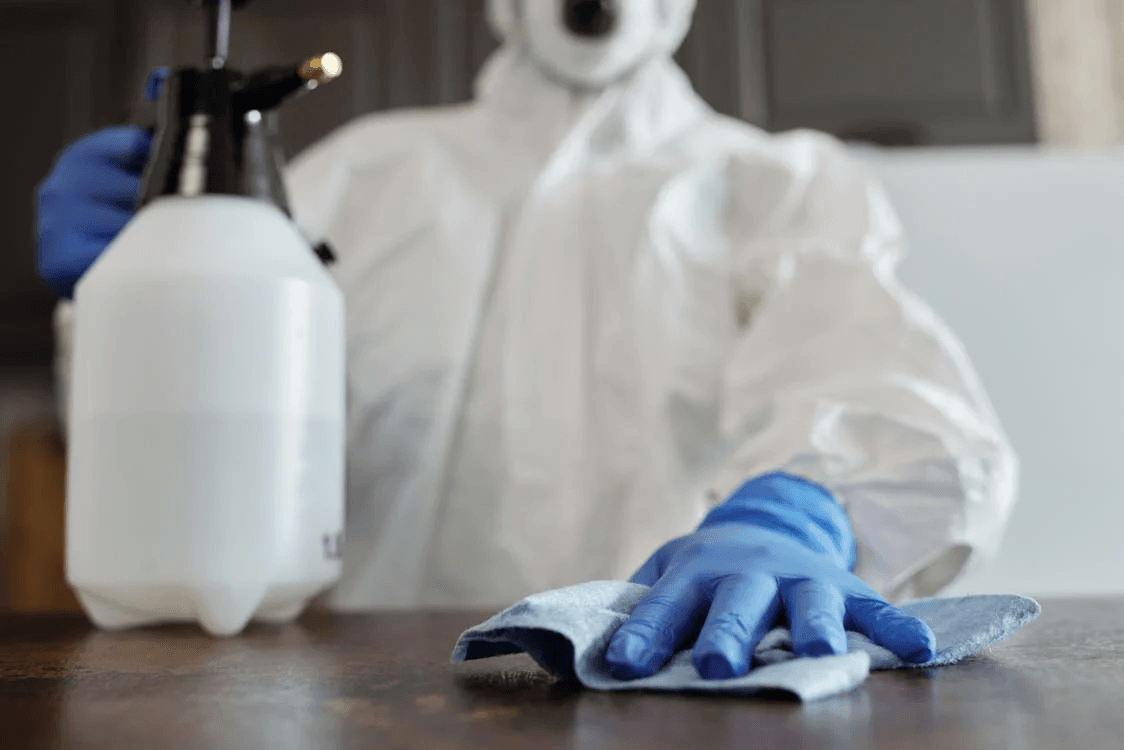 Exterminator in protective gear holding a pest control solution 